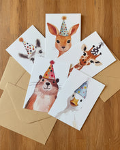 Load image into Gallery viewer, A set of five animal party greeting cards fanned out on a dark speckled surface with kraft paper envelopes. The cards feature watercolor illustrations of a squirrel, rabbit, duck, kangaroo, and giraffe wearing colorful party hats.